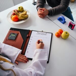 A nutritionist writes a weekly meal plan for a client in an office setting, surrounded by fresh fruits.